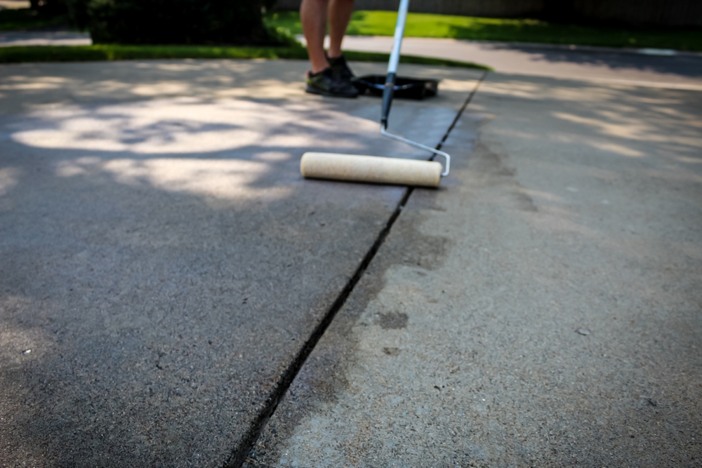A,Person,Sealing,A,Concrete,Driveway,With,A,Roller,Gliding