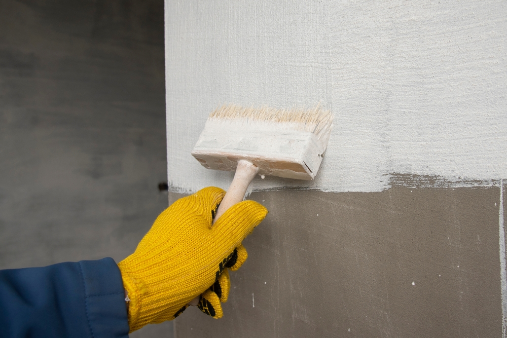 A,Worker,Is,Applying,Waterproofing,Paint,To,The,Wall.,Applying