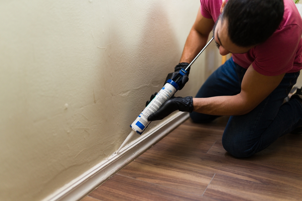 Handyman,Wearing,Black,Gloves,Applying,Silicone,Sealant,Between,Baseboard,And