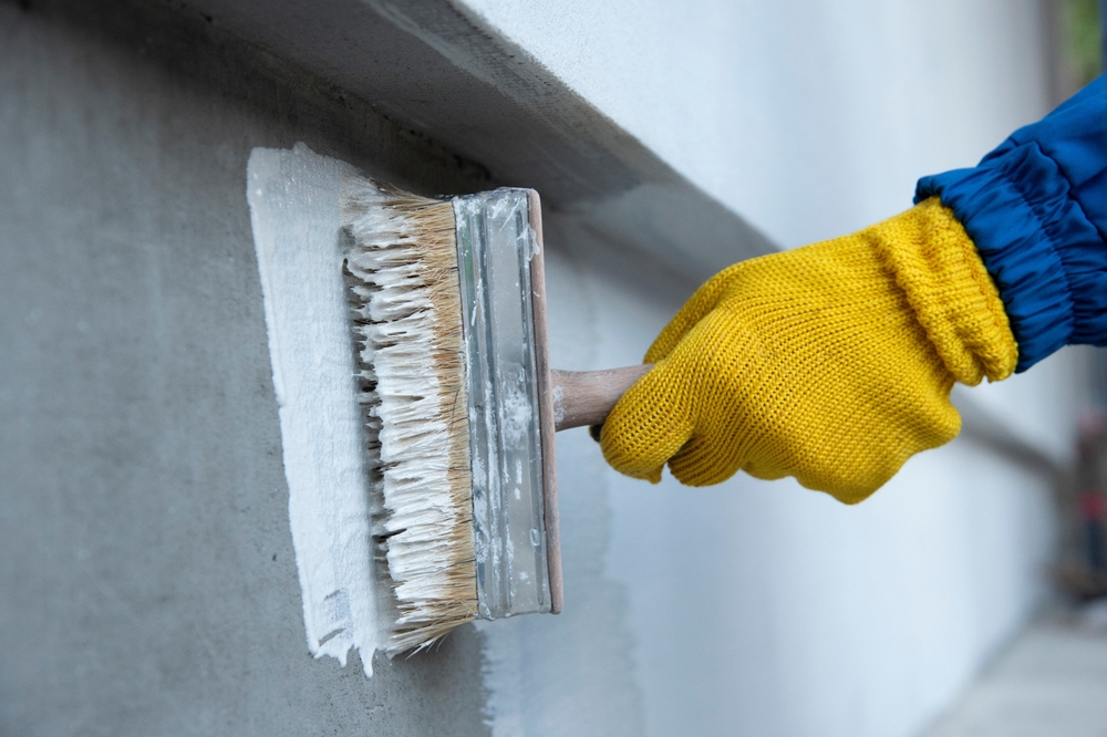 A,Worker,Is,Applying,Waterproofing,Paint,To,The,Wall.,Applying