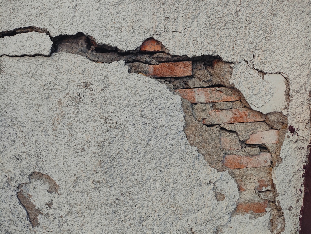 Close-up,Of,A,Cracked,And,Damaged,Wall,Revealing,Underlying,Bricks.