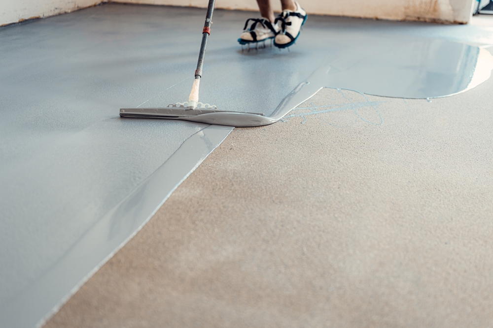 Construction,Worker,Applying,Epoxy,Resin,On,Concrete,Floor,Using,A