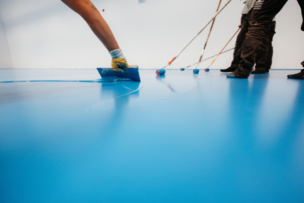 Workers,Applying,A,Blue,Epoxy,Resin,On,A,Floor,With
