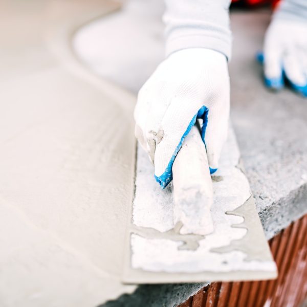 close-up of worker steel trowel and hand, using plastering tools