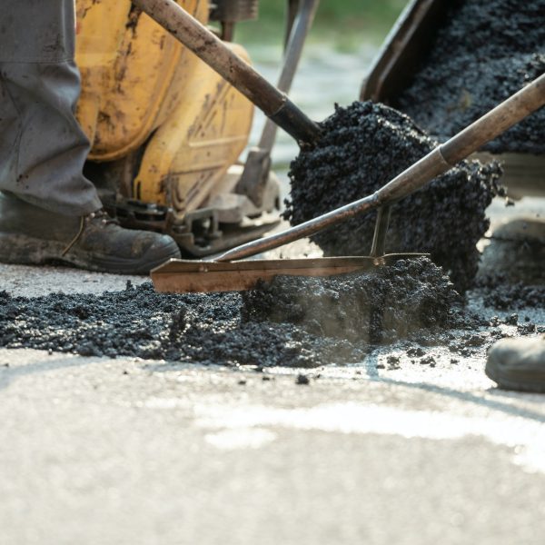 Two construction workers patching bump in the road