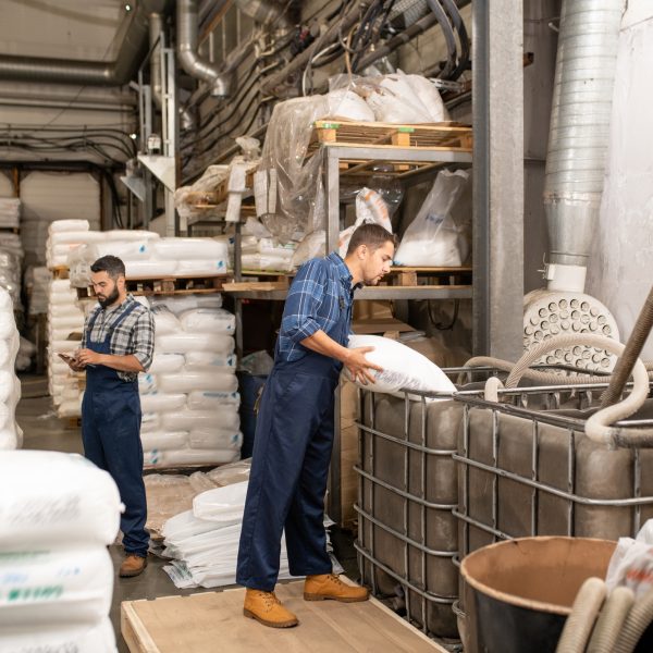 Young workers of large factory scattering polymer grains into huge container